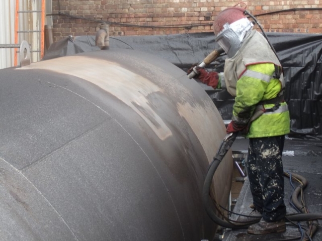 Man spraying a secondary containment tank with Chemcote coating